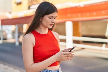 Young caucasian woman using smartphone with serious expression at street