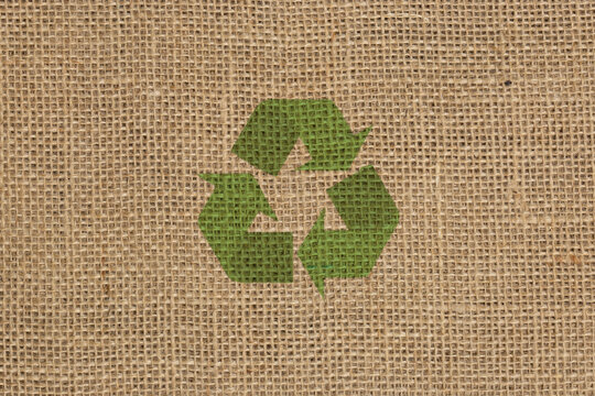 Recycling logo symbol on a hessian sack cloth material background