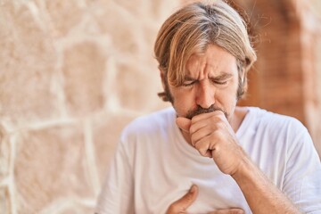 Young blond man coughing at street
