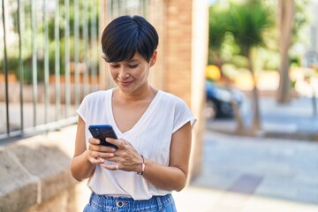 Middle age chinese woman smiling confident using smartphone at street