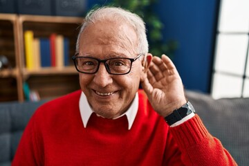 Senior man smiling confident using deafness hearing aid at home