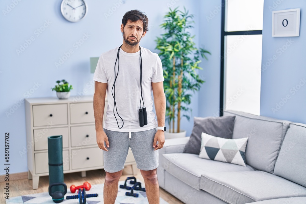 Poster handsome latin man wearing sportswear at home depressed and worry for distress, crying angry and afr