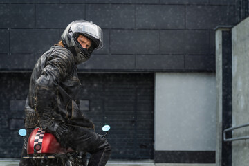 Biker sits on a motorcycle during a snowfall and looks back