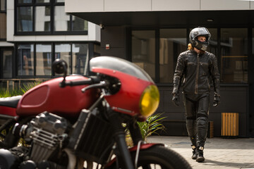 Fototapeta na wymiar Biker in protective clothing and helmet goes to motorcycle