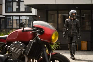 Fototapete Motorrad Biker in protective clothing and helmet goes to motorcycle