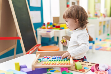Fototapeta premium Adorable hispanic girl playing with abacus standing at kindergarten