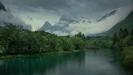 River landscape of Romsdalen with snowy mountains Troll Wall in Norway, moody rain weather with dark clouds