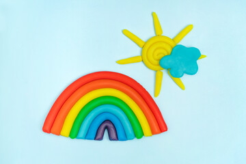Plasticine rainbow, cloud, sun with rays on blue background. Plasticine creativity, children's...