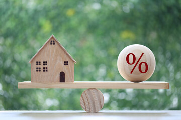 Interest rate up and Banking concept, Model house with Percentage symbol icon on wood scale seesaw...