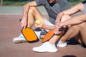  pickleball game, relaxing pickleball players couple with yellow ball with paddle sitting after...