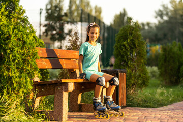 little girl wears roller skates on beautiful summer day in a park