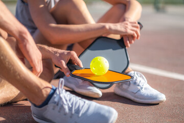  pickleball game, relaxing pickleball players couple with yellow ball with paddle sitting after...