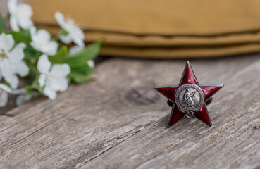 St. George's ribbon and the Order of the Red Star of the USSR World War II veteran on a wooden background. Translation into Russian: Workers of all countries unite. The concept of the May 9 holiday.