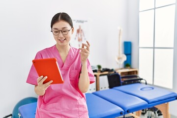 Young asian woman using touchpad device at physiotherapy clinic