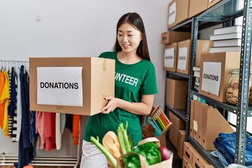 Young asian woman smiling with donated box at donations stand