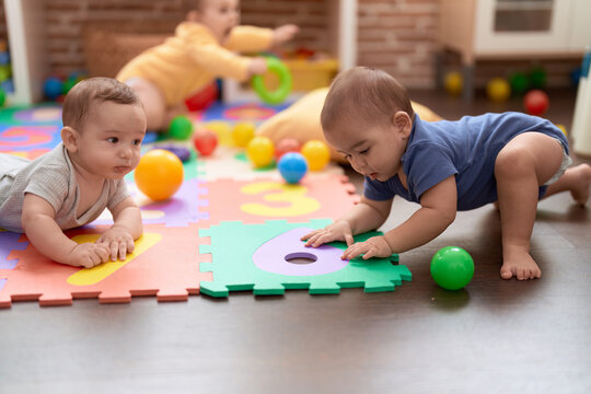 Group of toddlers playing with toys crawling on floor at kindergarten