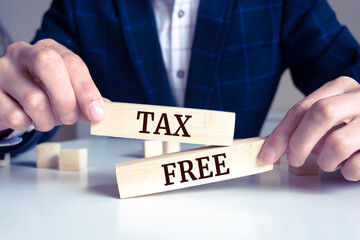 Closeup on businessman holding a wooden block with 	
Tax Free message, business concept