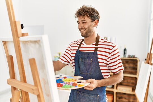 Young hispanic man smiling confident drawing at art studio
