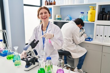 Young two people working at scientist laboratory smiling happy pointing with hand and finger