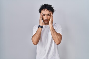 Hispanic man standing over isolated background with hand on head, headache because stress. suffering migraine.