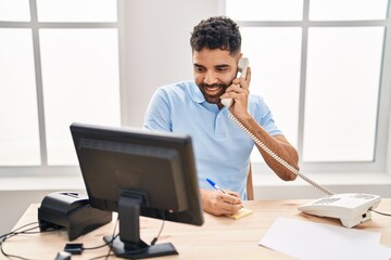 Obraz premium Young hispanic man business worker using talking on telephone at office