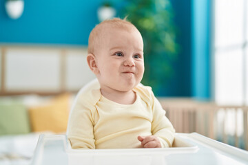 Fototapeta premium Adorable caucasian baby sitting on highchair at bedroom