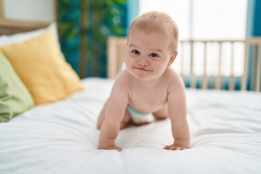 Adorable caucasian baby smiling confident crawling on bed at bedroom