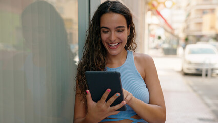 Young beautiful hispanic woman smiling confident using touchpad at street