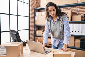 Young hispanic woman ecommerce business worker using laptop at office