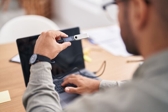 Young hispanic man using crypto cold wallet at office