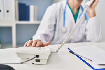 Young caucasian man doctor talking on telephone at clinic