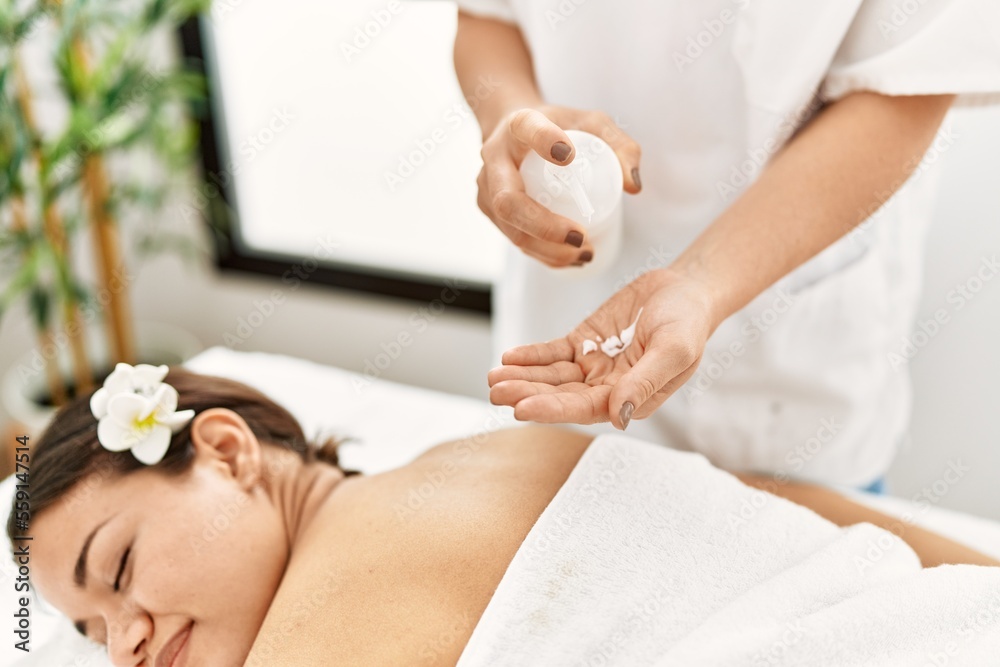 Poster young latin woman relaxed having back massage with moisturizer at beauty center