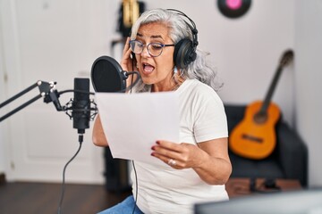 Middle age woman musician singing song at music studio