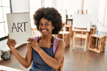Young african american woman smiling confident holding notebook at art studio