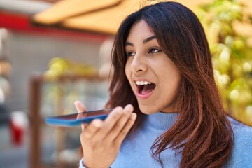 Young hispanic woman smiling confident talking on the smartphone at street