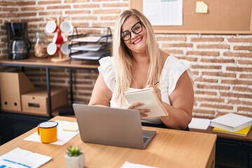 Young woman business worker using laptop writing on notebook at office