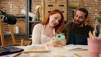 Man and woman couple using smartphone and drawing at art studio