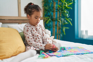 Adorable hispanic girl playing maths game sitting on bed at bedroom