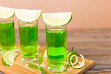 Sweet refreshing mint liqueur, with ice and mint leaves on table background, Shots with lime slice and mint flat lay