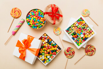 Set of different sweet candy in a paper box with a satin ribbon on a colored background. Holiday concept
