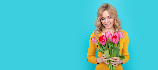 happy young blonde woman with spring tulip flowers on blue background. Woman isolated face portrait, banner with mock up copy space.