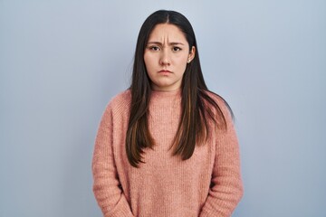 Fototapeta premium Young latin woman standing over blue background skeptic and nervous, frowning upset because of problem. negative person.
