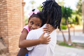 Father and daughter smiling confident hugging each other at street