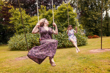 beautiful middle-aged couple of friends swinging on children's swings