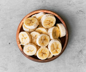 Photo of banana slices in a bowl on a concrete surface