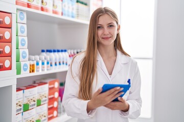 Young caucasian woman pharmacist using touchpad working at pharmacy