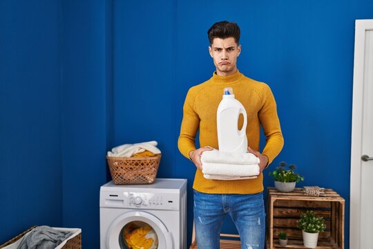 Young hispanic man holding clean towels depressed and worry for distress, crying angry and afraid. sad expression.