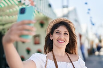 Young hispanic woman tourist smiling confident make selfie by smartphone at street