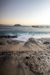 Beautiful morning on the sandy beach. Long exposure at the sea. Milky sunrise in haze and fog. Corralejo, Canary Islands, Spain