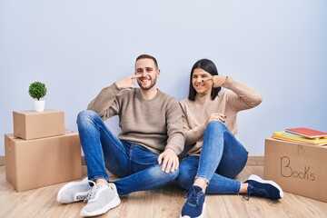 Young couple moving to a new home pointing with hand finger to face and nose, smiling cheerful. beauty concept